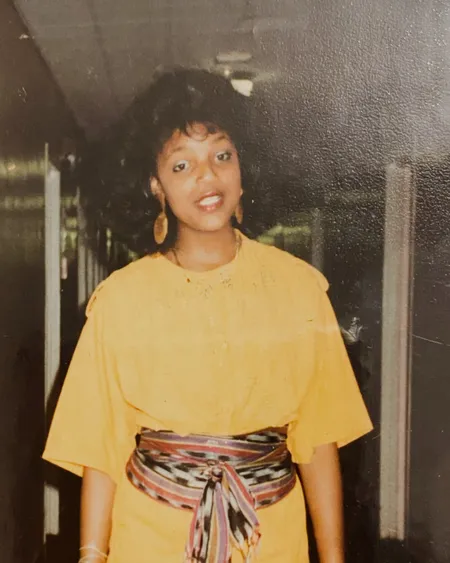 Tami in her college years, in a yellow jumpsuit and sash